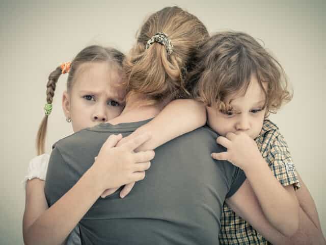 Upset children hugging their mother